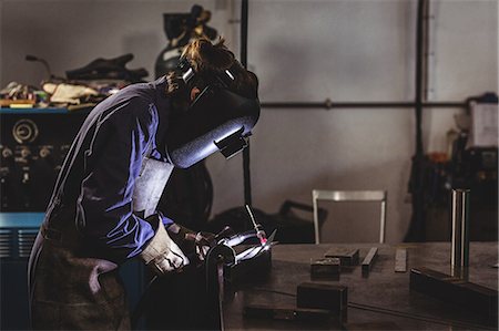 simsearch:6109-08722835,k - Female welder working on a piece of metal in workshop Foto de stock - Sin royalties Premium, Código: 6109-08722862