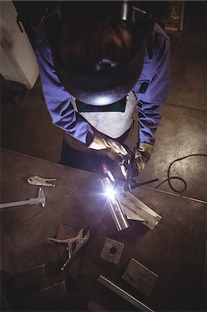 simsearch:6109-08722790,k - Female welder working on a piece of metal in workshop Foto de stock - Sin royalties Premium, Código: 6109-08722867