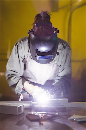 simsearch:6109-08722895,k - Female welder working on a piece of metal in workshop Stock Photo - Premium Royalty-Free, Code: 6109-08722872
