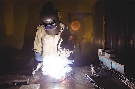 simsearch:6109-08722790,k - Female welder working on a piece of metal in workshop Foto de stock - Sin royalties Premium, Código: 6109-08722877