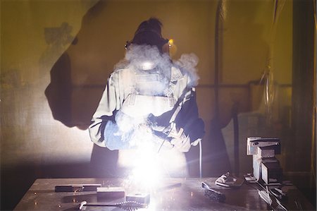 simsearch:6109-08722835,k - Female welder working on a piece of metal in workshop Foto de stock - Sin royalties Premium, Código: 6109-08722875