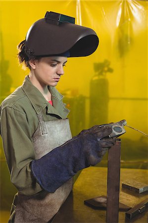simsearch:6109-08722895,k - Female welder examining a piece of metal in workshop Stock Photo - Premium Royalty-Free, Code: 6109-08722878