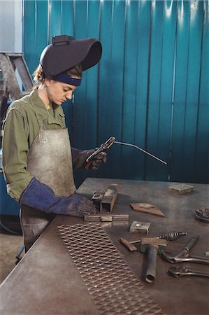 simsearch:6109-08722895,k - Female welder holding welding arch in workshop Stock Photo - Premium Royalty-Free, Code: 6109-08722883