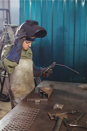 simsearch:6109-08722895,k - Female welder holding welding arch in workshop Stock Photo - Premium Royalty-Free, Code: 6109-08722884