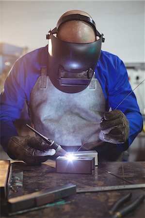 simsearch:6109-08722895,k - Male welder working on a piece of metal in workshop Foto de stock - Sin royalties Premium, Código: 6109-08722803