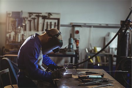 simsearch:6109-08722835,k - Male welder working on a piece of metal in workshop Foto de stock - Sin royalties Premium, Código: 6109-08722807