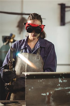 simsearch:6109-08722895,k - Female welder holding welding torch in workshop Stock Photo - Premium Royalty-Free, Code: 6109-08722804