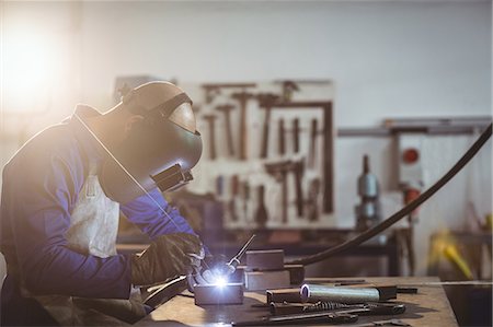 simsearch:6109-08722835,k - Male welder working on a piece of metal in workshop Foto de stock - Sin royalties Premium, Código: 6109-08722805