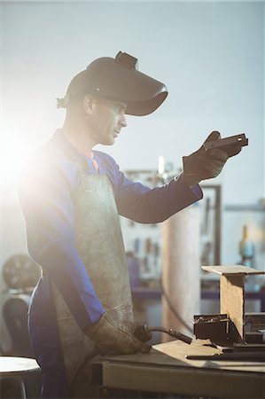 simsearch:6109-08722814,k - Male welder examining a piece of metal in workshop Foto de stock - Royalty Free Premium, Número: 6109-08722809