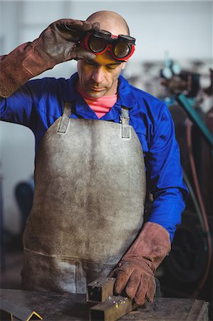 simsearch:6109-08722814,k - Male welder examining a piece of metal in workshop Foto de stock - Royalty Free Premium, Número: 6109-08722815