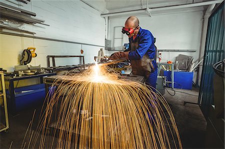 simsearch:6109-08722835,k - Male welder working on a piece of metal in workshop Foto de stock - Sin royalties Premium, Código: 6109-08722822