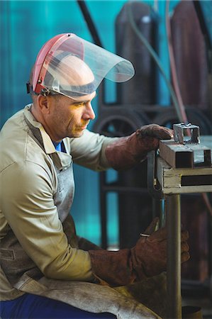 Male welder examining a piece of metal in workshop Stock Photo - Premium Royalty-Free, Code: 6109-08722837
