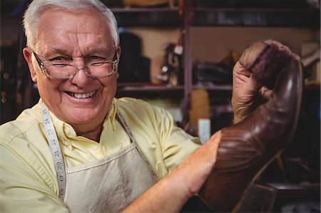 Portrait of shoemaker holding a shoe in workshop Stock Photo - Premium Royalty-Free, Code: 6109-08722943