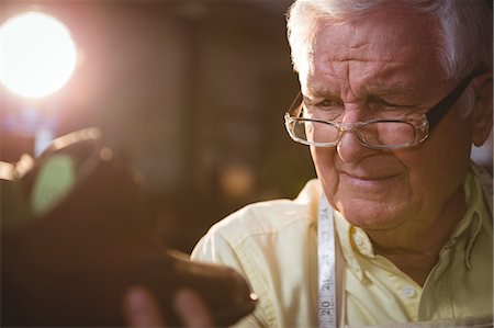 simsearch:6109-08722971,k - Shoemaker examining a shoe in workshop Foto de stock - Royalty Free Premium, Número: 6109-08722941