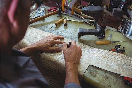 simsearch:6109-08722971,k - Shoemaker cutting a piece of material in workshop Foto de stock - Royalty Free Premium, Número: 6109-08722985