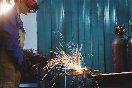 simsearch:6118-08729041,k - Female welder working on a piece of metal in workshop Stock Photo - Premium Royalty-Free, Code: 6109-08722900