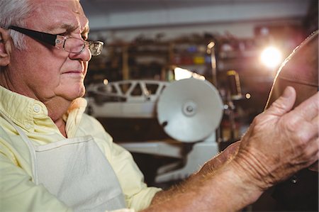 shoes store old age - Shoemaker examining a shoe in workshop Stock Photo - Premium Royalty-Free, Code: 6109-08722932
