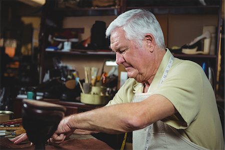 shoes store old age - Shoemaker cutting a piece of leather in workshop Stock Photo - Premium Royalty-Free, Code: 6109-08723006