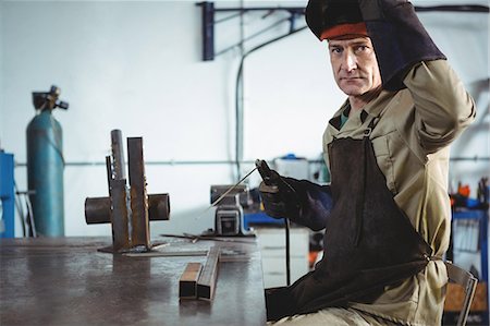 simsearch:6109-08700797,k - Portrait of welder holding welding machine in workshop Fotografie stock - Premium Royalty-Free, Codice: 6109-08739083