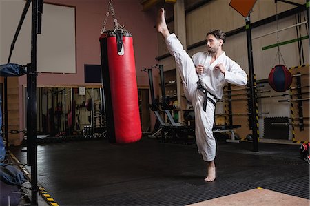 simsearch:6109-08739241,k - Man practicing karate with punching bag in fitness studio Photographie de stock - Premium Libres de Droits, Code: 6109-08739189