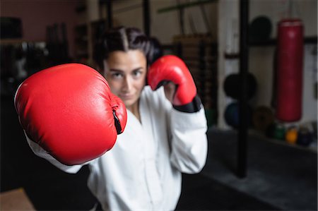 simsearch:6109-08739241,k - Portrait of woman in boxing gloves at fitness studio Photographie de stock - Premium Libres de Droits, Code: 6109-08739249