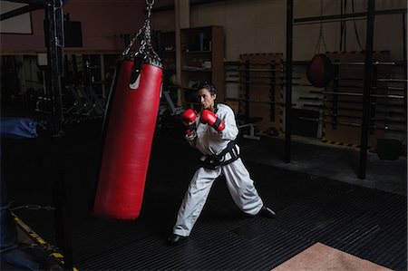 Woman practicing karate with punching bag in fitness studio Fotografie stock - Premium Royalty-Free, Codice: 6109-08739251