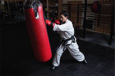 Woman practicing karate with punching bag in fitness studio Stock Photo - Premium Royalty-Free, Code: 6109-08739252