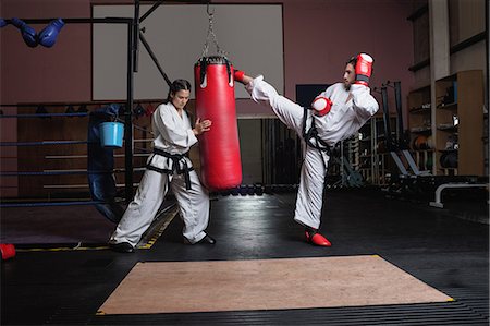 simsearch:6109-08739282,k - Man and woman practicing karate with punching bag in studio Photographie de stock - Premium Libres de Droits, Code: 6109-08739200