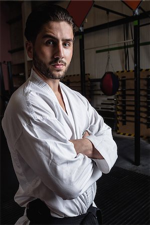 Portrait of man in karategi standing with arms crossed in fitness studio Foto de stock - Sin royalties Premium, Código: 6109-08739208