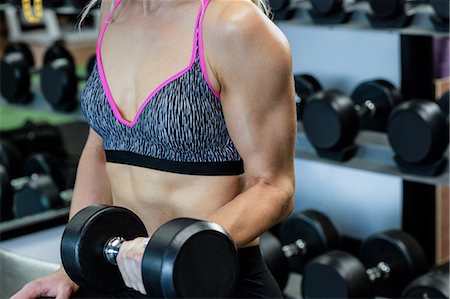 simsearch:6109-08739549,k - Mid-section of woman lifting dumbbells at gym Stock Photo - Premium Royalty-Free, Code: 6109-08739526
