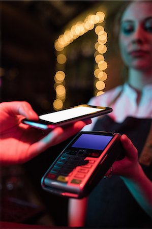 pay with device - Customer making payment through smart phone in bar Stock Photo - Premium Royalty-Free, Code: 6109-08801987