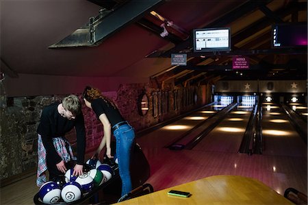 Two young people sorting bowling balls in the bowling alley Stock Photo - Premium Royalty-Free, Code: 6109-08802001