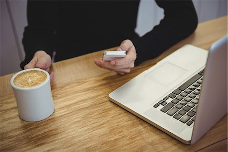 simsearch:6109-08944970,k - Mid section of man using mobile phone while having coffee in the coffee shop Photographie de stock - Premium Libres de Droits, Code: 6109-08802115