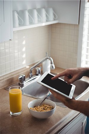 simsearch:6109-08802258,k - Mid section of man using his digital tablet in the kitchen at home Photographie de stock - Premium Libres de Droits, Code: 6109-08802251