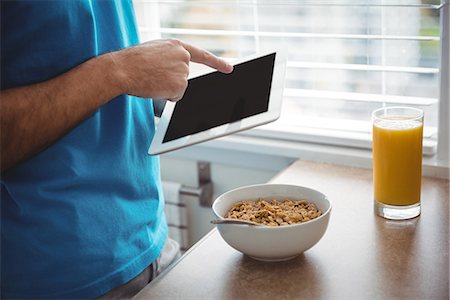 simsearch:6109-08802258,k - Mid section of man using his digital tablet in the kitchen at home Photographie de stock - Premium Libres de Droits, Code: 6109-08802255