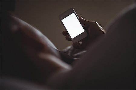 simsearch:6109-08489144,k - Man using his mobile phone while relaxing in bed at home Stock Photo - Premium Royalty-Free, Code: 6109-08802279