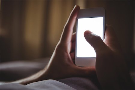 people on smart phone - Close-up of mans hand using mobile phone in bedroom Stock Photo - Premium Royalty-Free, Code: 6109-08802284