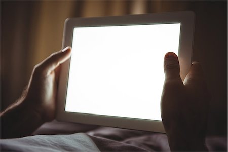 Close-up of mans hand using digital tablet in bedroom at home Photographie de stock - Premium Libres de Droits, Code: 6109-08802285