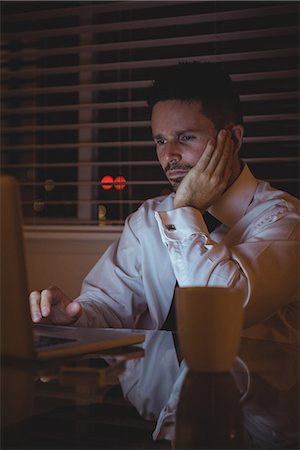 simsearch:6109-08802258,k - Thoughtful businessman using laptop in living room at home Photographie de stock - Premium Libres de Droits, Code: 6109-08802225