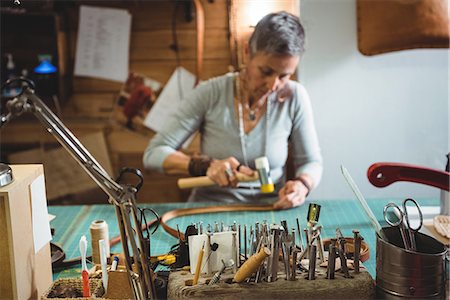 Craftswoman hammering leather in workshop Foto de stock - Sin royalties Premium, Código: 6109-08802346