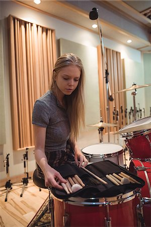 Woman looking at drum sticks in recording studio Stock Photo - Premium Royalty-Free, Code: 6109-08802440