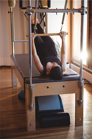 exercising on a machine - Woman practicing on pilates reformer in fitness studio Stock Photo - Premium Royalty-Free, Code: 6109-08802568
