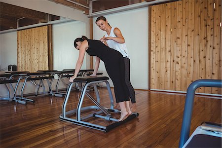 simsearch:6102-08120793,k - Trainer helping a woman while practicing pilates in fitness studio Foto de stock - Royalty Free Premium, Número: 6109-08802503