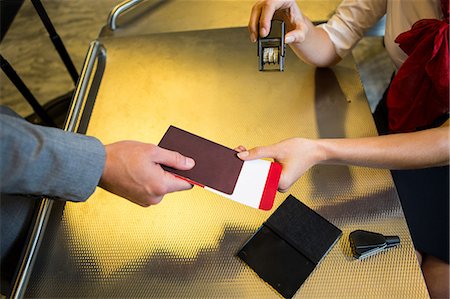 Airline check-in attendant handing passport to passenger at airport check-in counter Photographie de stock - Premium Libres de Droits, Code: 6109-08802681