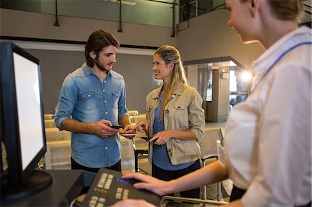 Couple interacting with each other at the check in counter in airport terminal Stock Photo - Premium Royalty-Free, Code: 6109-08802687