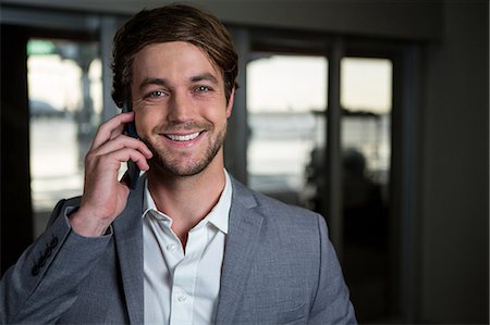 Portrait smiling businessman talking on his mobile phone in the airport terminal Stock Photo - Premium Royalty-Free, Code: 6109-08802685