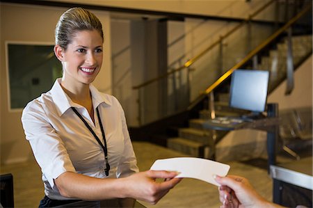 Female staff giving ticket to passenger in the airport terminal Stock Photo - Premium Royalty-Free, Code: 6109-08802740