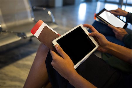 Mid-section of woman using digital tablet in waiting area at airport Stock Photo - Premium Royalty-Free, Code: 6109-08802761