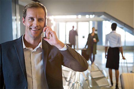 Businessman talking on mobile phone in waiting area at airport terminal Stock Photo - Premium Royalty-Free, Code: 6109-08802770