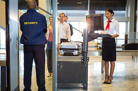 simsearch:6109-08722619,k - Airport security guard with passenger walking through body scanner at airport terminal Foto de stock - Sin royalties Premium, Código: 6109-08802798